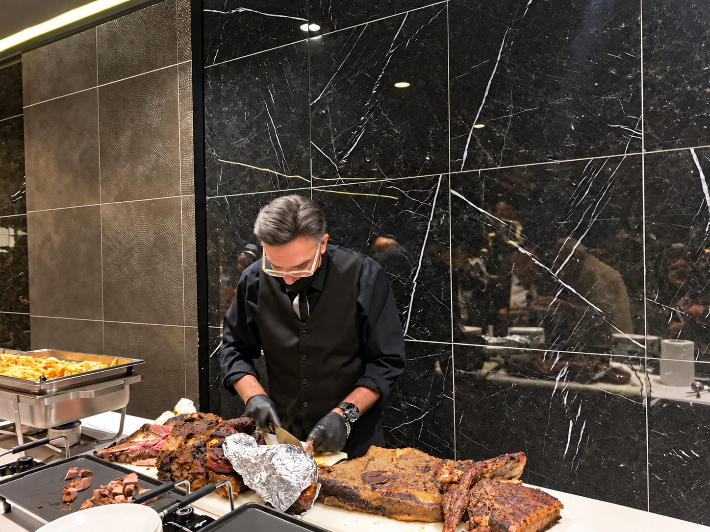 Un maître d’hôtel découpe les viandes fumées devant les invités