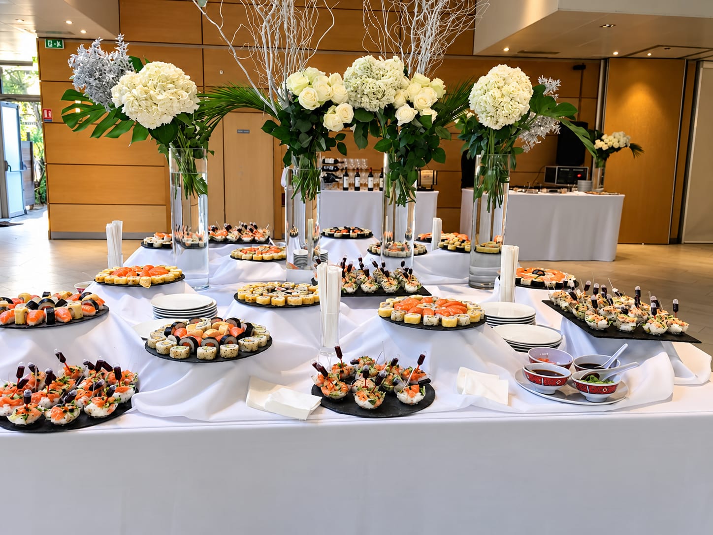 Buffet japonais dressé de sushis, de makis et de verrines entre des hortensias blancs