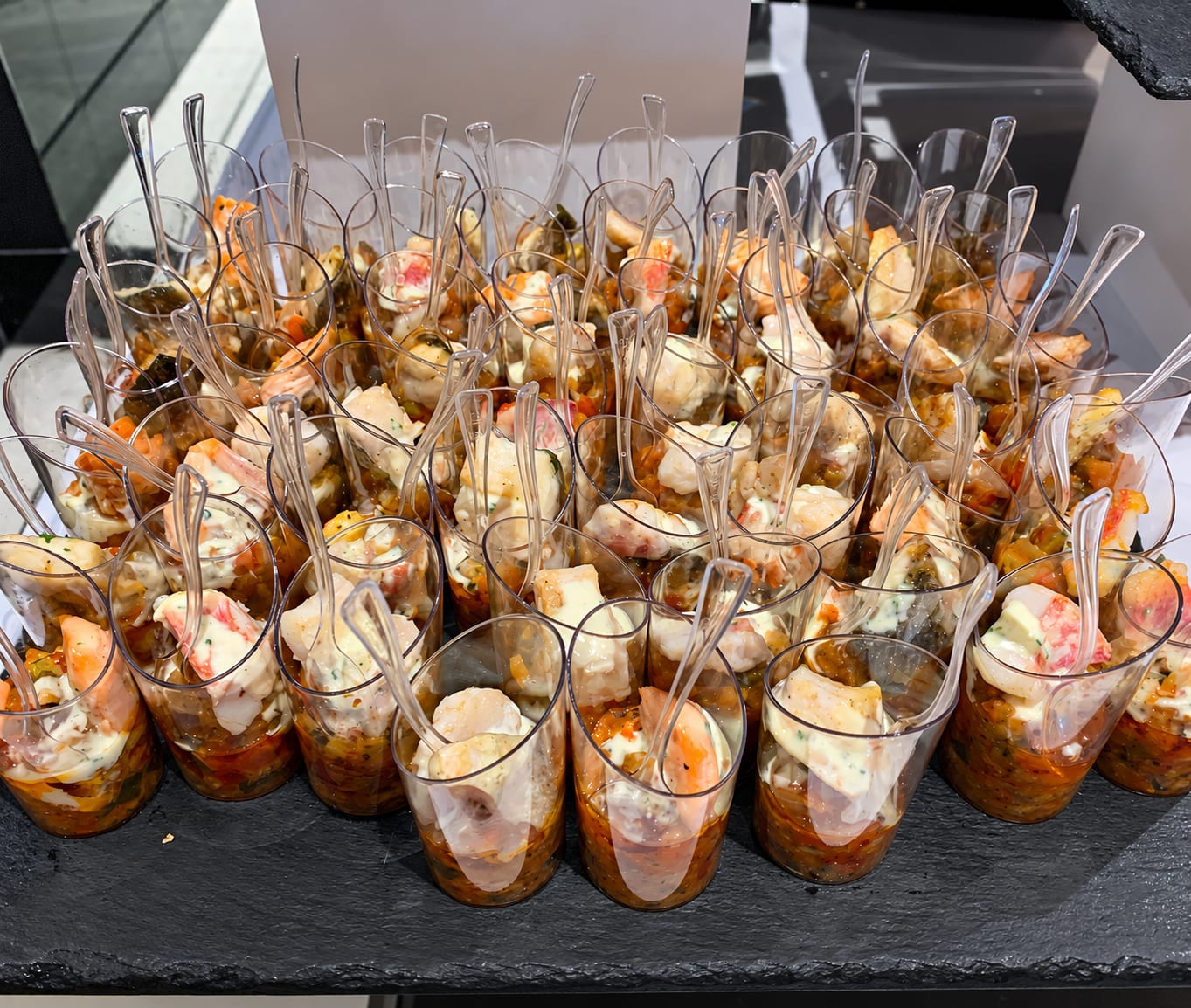 Verrines de crevettes et de crabe sur un lit de légumes, sur une ardoise