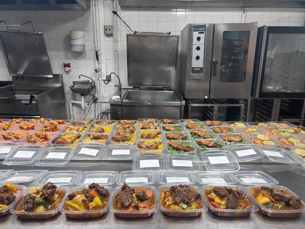 Cuisine professionnelle : barquettes alignées sur un plan de travail en inox, prêtes à être fermées