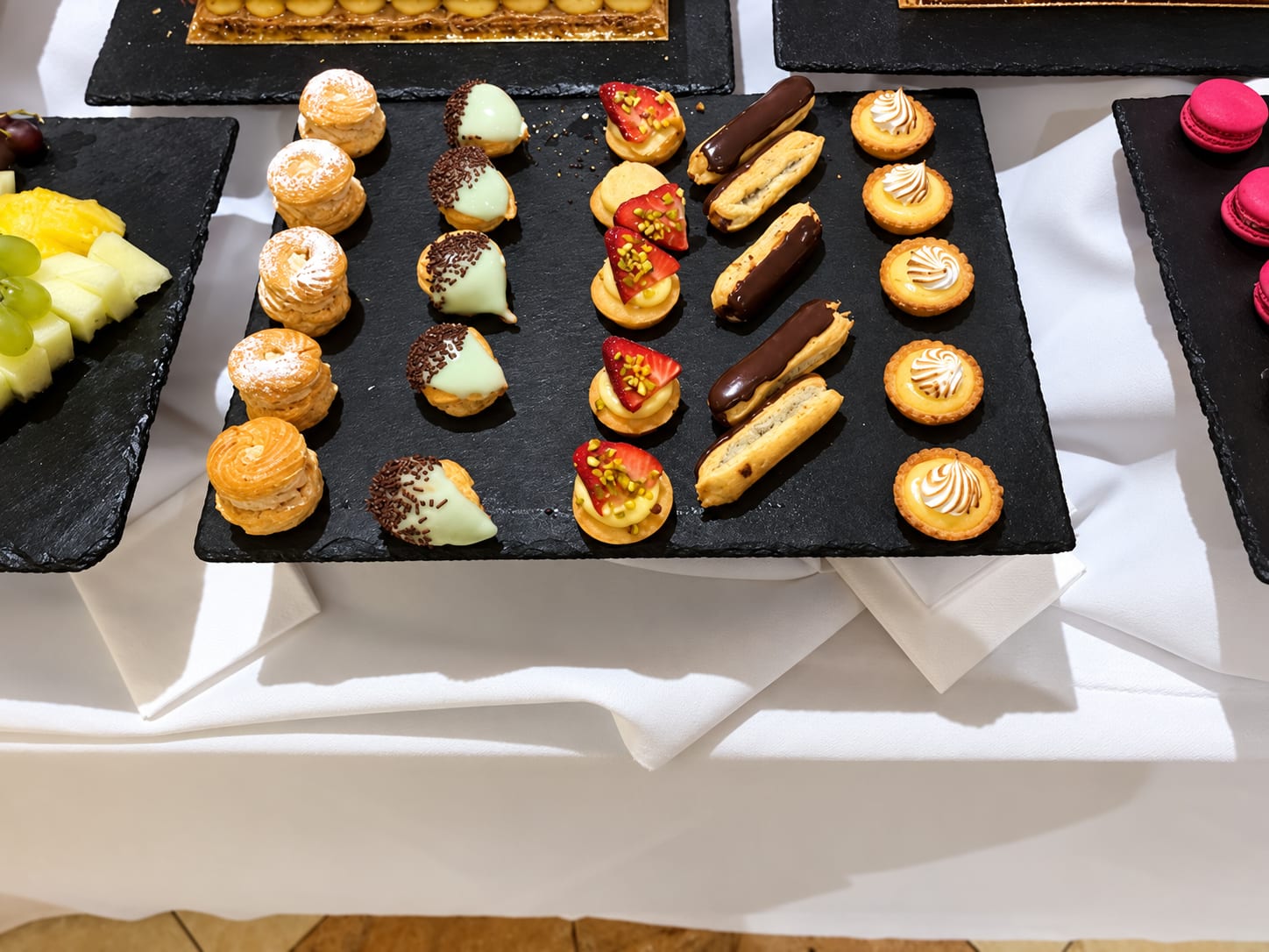Ardoise de mignardises : choux, éclairs au chocolat, tartelettes aux fraises et tartelettes au citron meringuées